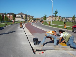Crew finishing a red stamped-concrete traffic calming median in a subdivision